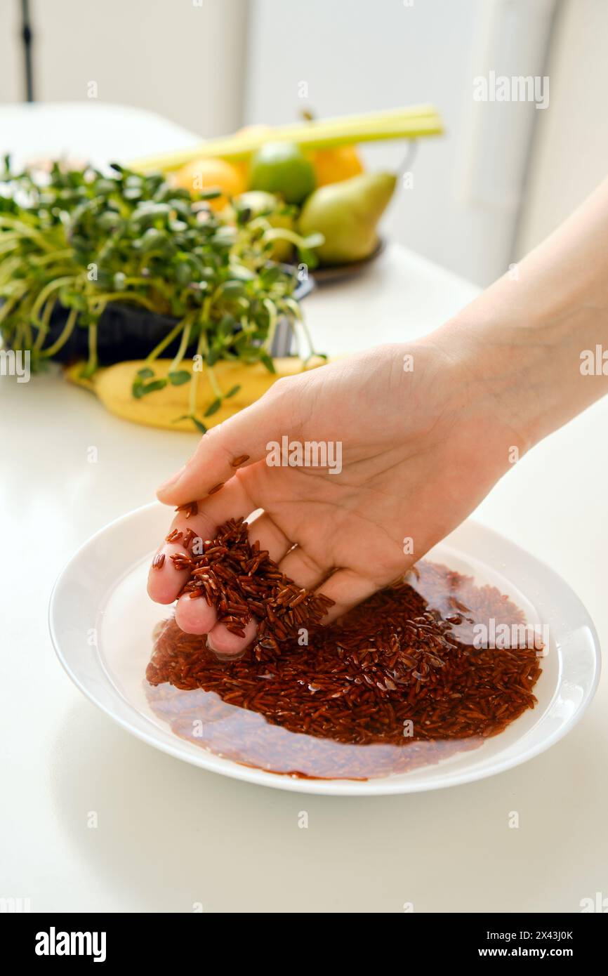 Vista ravvicinata del riso rosa lavato a mano in una ciotola Foto Stock