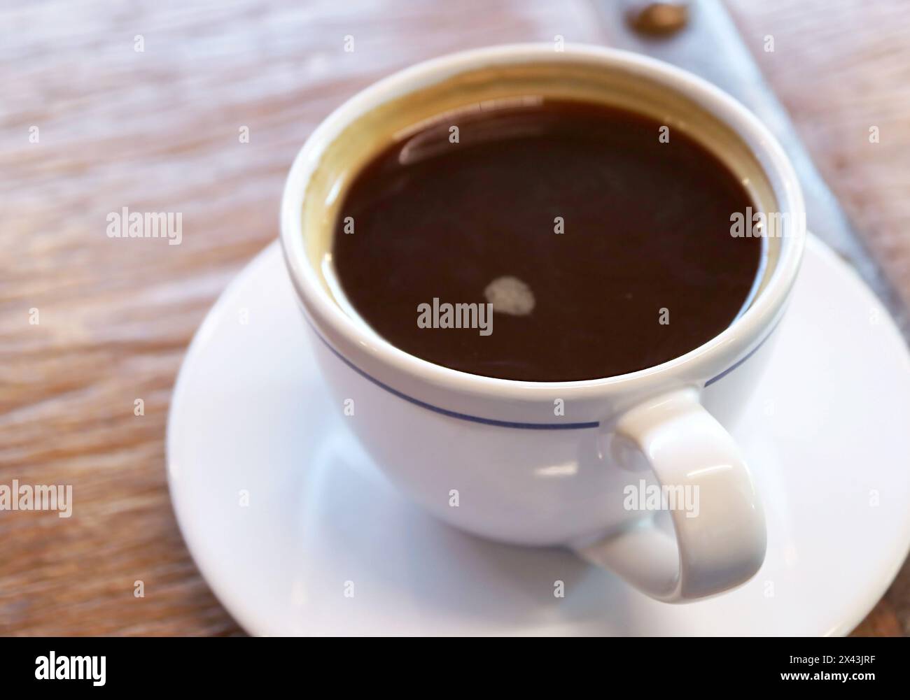Primo piano di una tazza di caffè nero isolato su un tavolo di legno Foto Stock