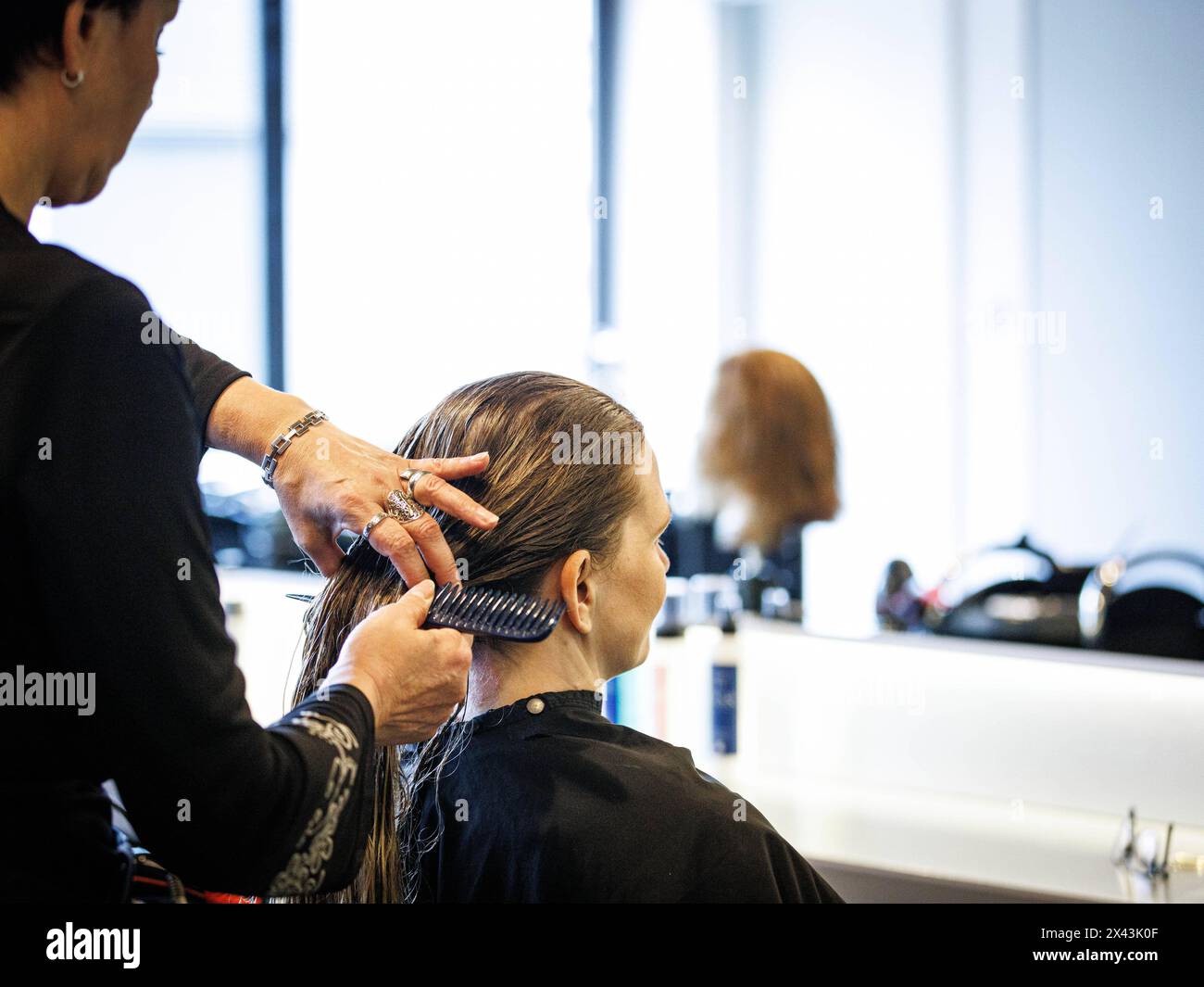 Eine Friseurin kaemmt die Haare ihrer Kundin, aufgenommen im Friseursalon Coiffeur Sivan a Berlino, 22.04.2024. Berlin Deutschland *** parrucchiere c Foto Stock