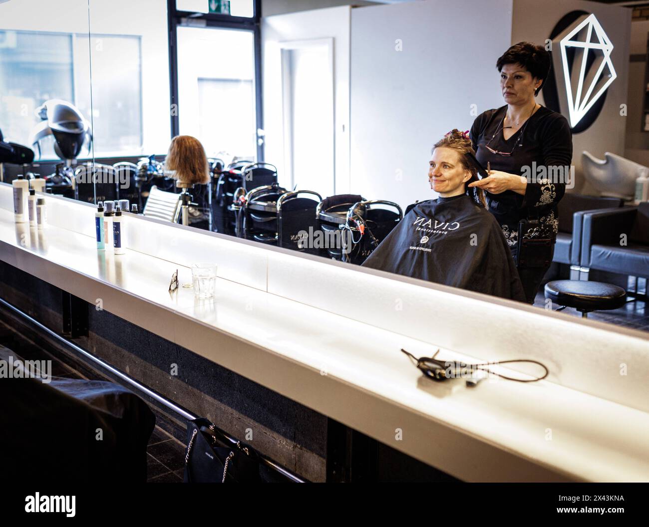 Valentyna Vysotska, Friseurin aus der Ukraine, kaemmt die Haare ihrer Kundin, aufgenommen im Friseursalon Coiffeur Sivan a Berlino, 22.04.2024. Berlino Foto Stock