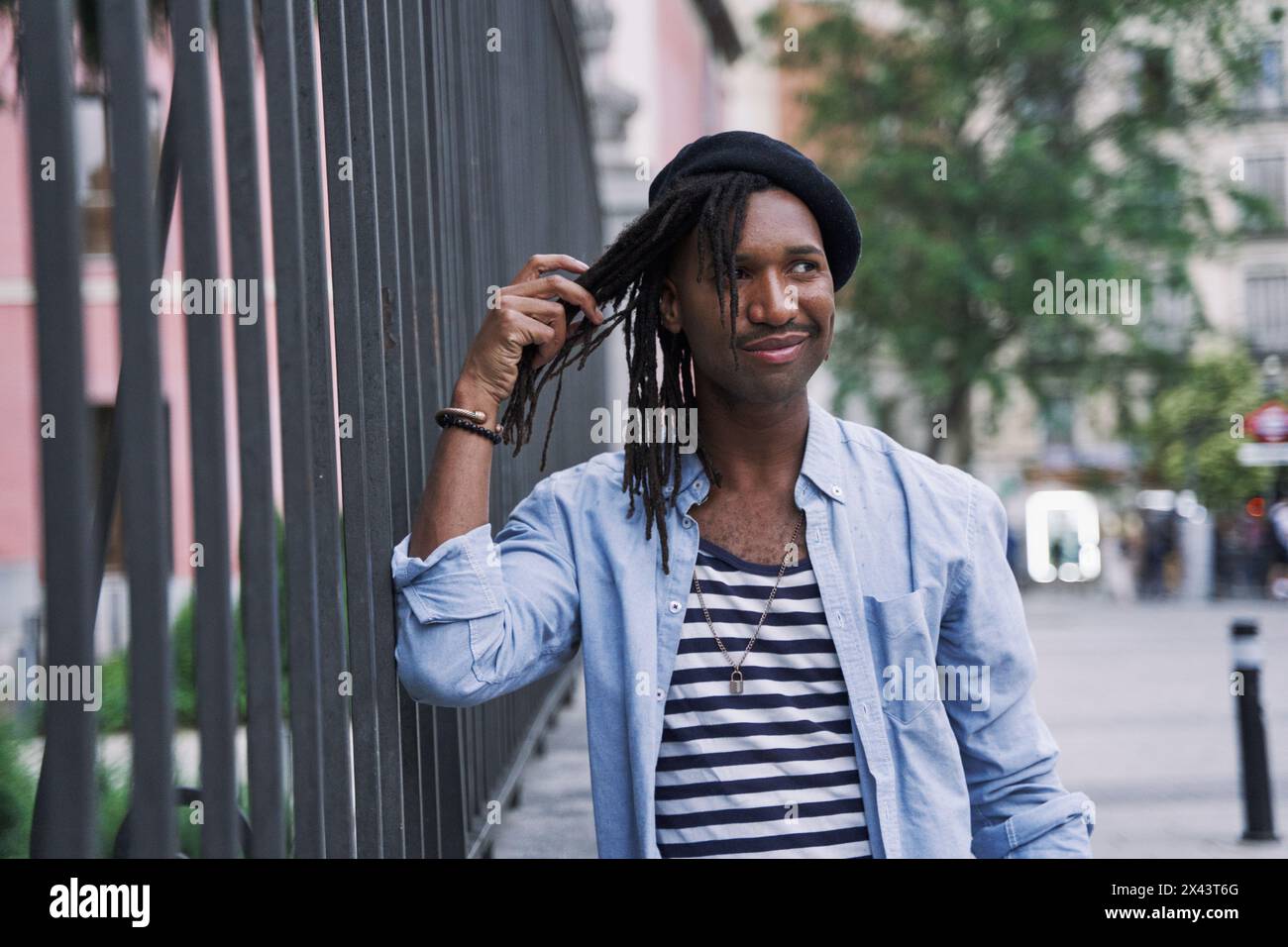 ritratto di un giovane millenario che si allunga sulle lunghe trecce o sui dreadlock Foto Stock