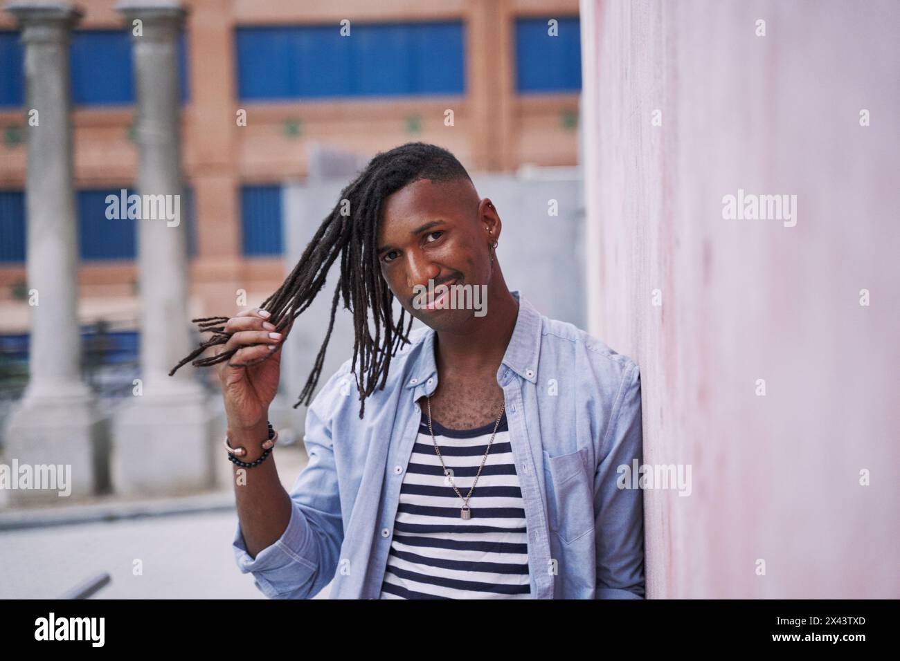 ritratto di un giovane millenario che si allunga sulle lunghe trecce o sui dreadlock Foto Stock