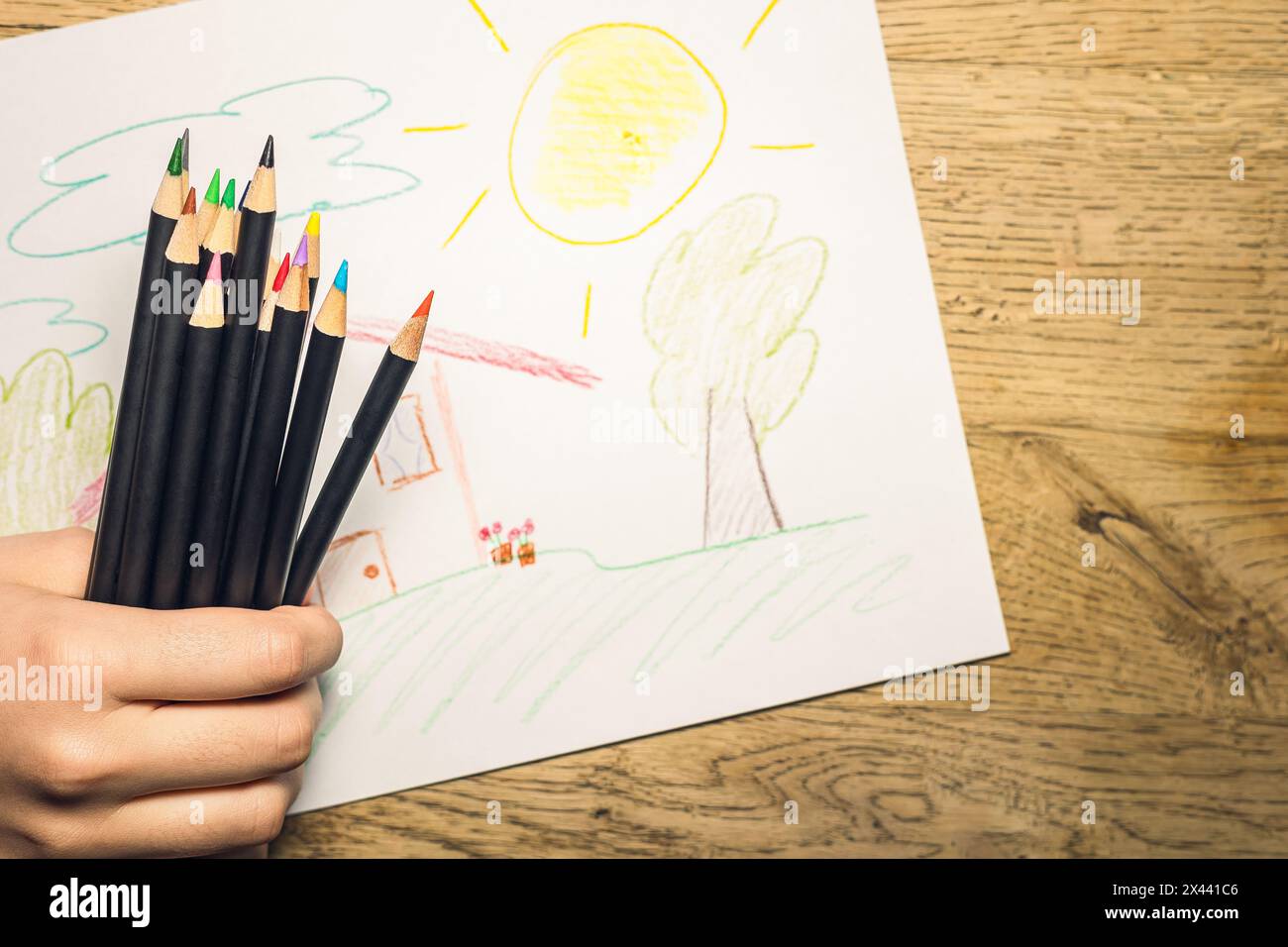 mano di una ragazza con matite colorate accanto a un quadro dipinto con le matite Foto Stock