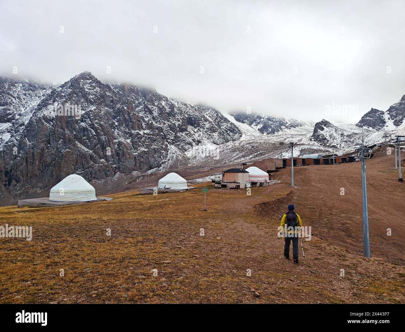 Si snoda su un altopiano di montagna con cime innevate sullo sfondo, sotto un cielo nuvoloso. Foto Stock