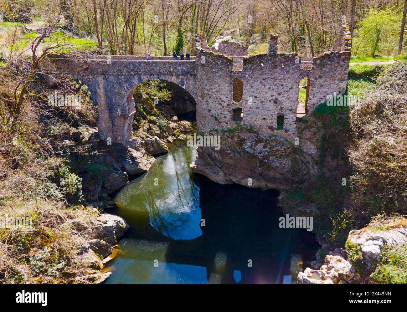 Vecchio ponte in pietra parzialmente distrutto su un fiume, circondato da vegetazione lussureggiante, Ponte del Diavolo, Pont de Diable, Ponte in pietra romanica, Ariege Foto Stock