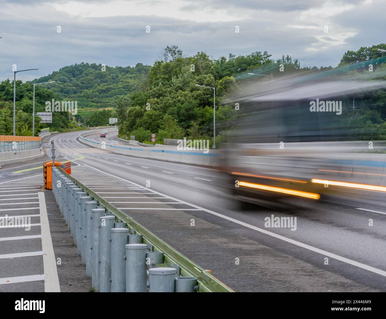 Strisce di luce e sfocature di veicoli di passaggio in autostrada in posizione di campagna durante l'ora blu sotto i cieli nuvolosi in Corea del Sud Foto Stock