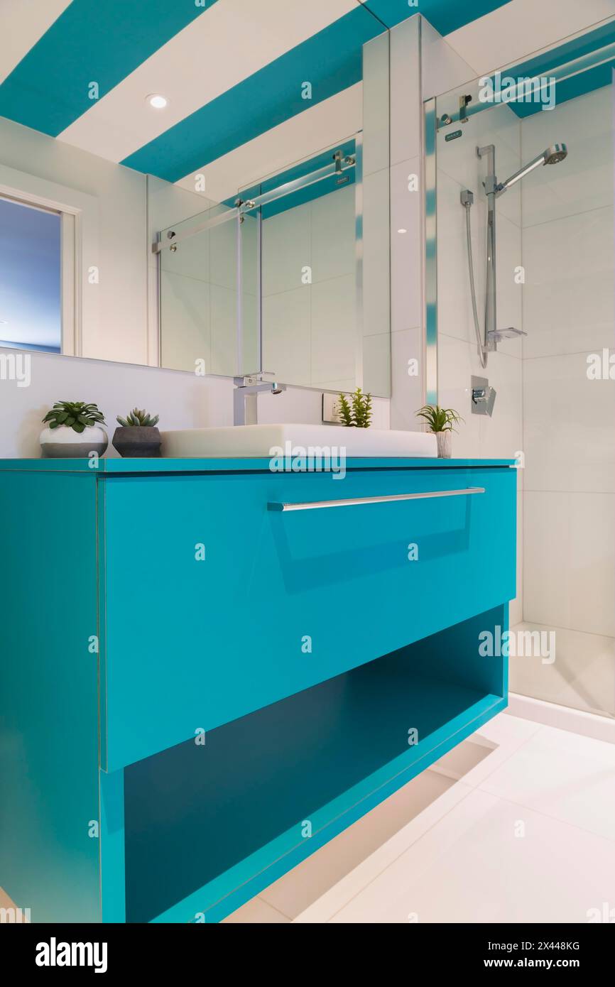 Lavandino laminato blu con lavandino bianco di forma rettangolare, box doccia in vetro trasparente nel bagno degli ospiti con pavimento piastrellato in ceramica bianca e blu e bianco Foto Stock