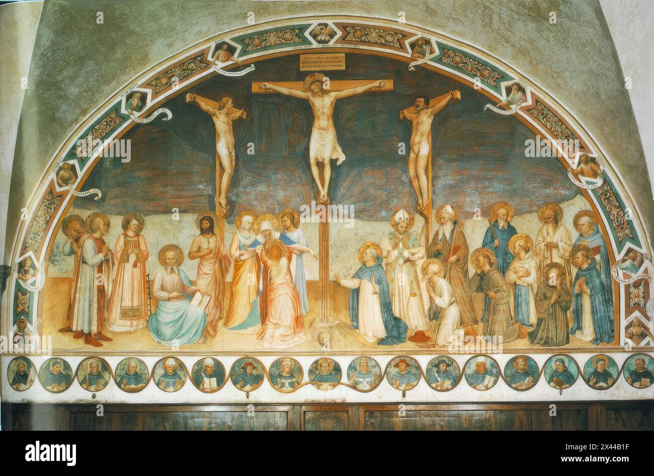 ANGELICO, fra (nato ca. 1400, Vicchio nel Mugello, d. 1455, Roma) Crocifissione e Santi 1441-42 affresco, 550 x 950 cm Convento di San Marco, Firenze l'affresco gigante occupa l'intera parete di fronte all'ingresso della sala Capitolare. I santi raffigurati sono, da sinistra: Cosma e Damiano, Lorenzo, Marco Evangelista, Giovanni Battista, la Vergine e le pie donne; a destra della Cricifissione inginocchiato Domenico, Girolamo, Francesco, Bernardo, Giovanni Gualberto e Pietro il Martire, in piedi Zanobi (o forse Ambrogio), Augustin, Benedetto, Romualdo e Tommaso d'Aquino. Intorno all'affresco, o Foto Stock