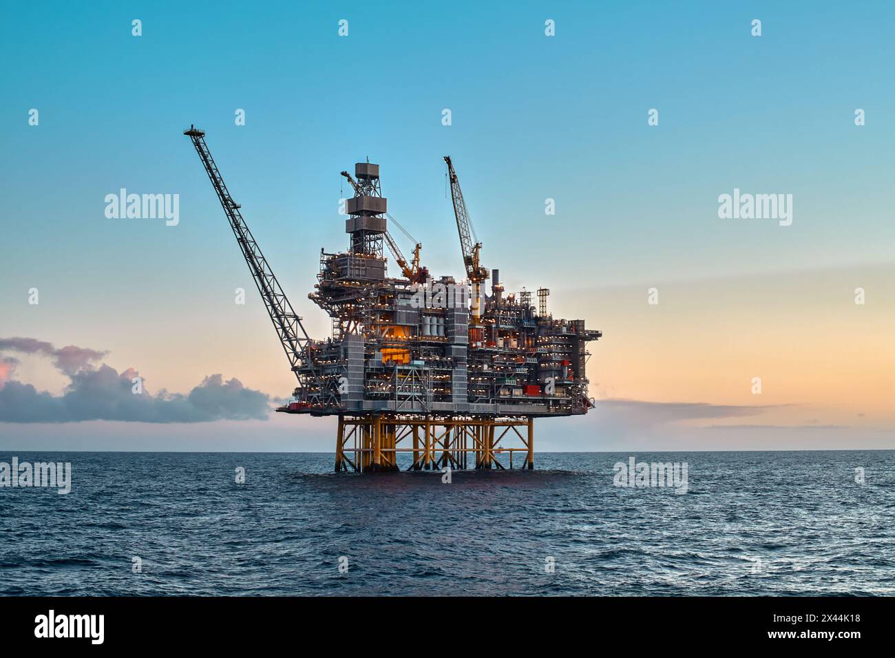 Piattaforma offshore per giacimenti di petrolio e gas nell'oceano durante uno splendido tramonto colorato. Foto Stock