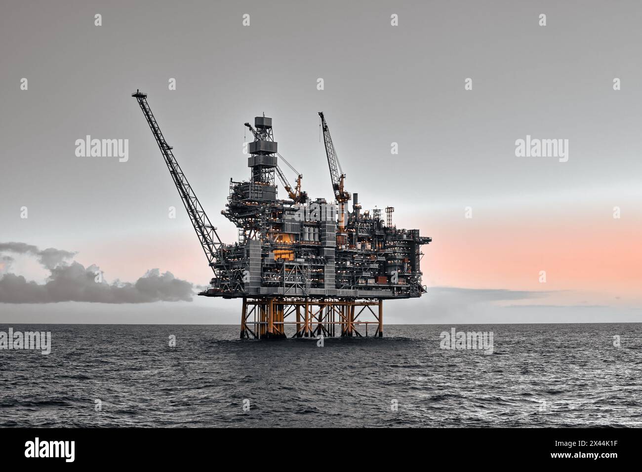 Piattaforma offshore per giacimenti di petrolio e gas nell'oceano durante il tramonto. Foto Stock