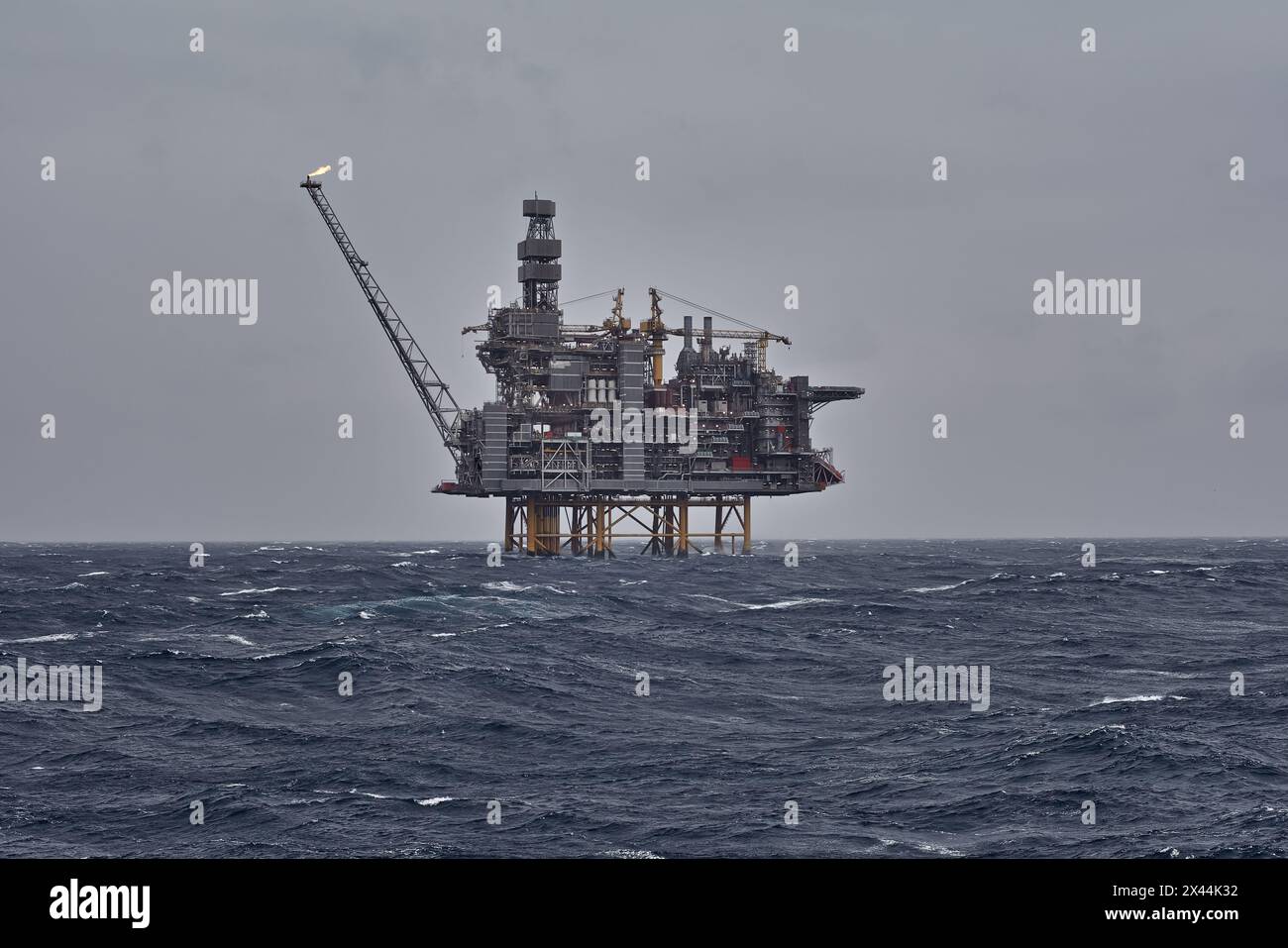 Vista della piattaforma di jackup offshore all'orizzonte in una giornata grigia nuvolosa nel mare con le onde. Foto Stock