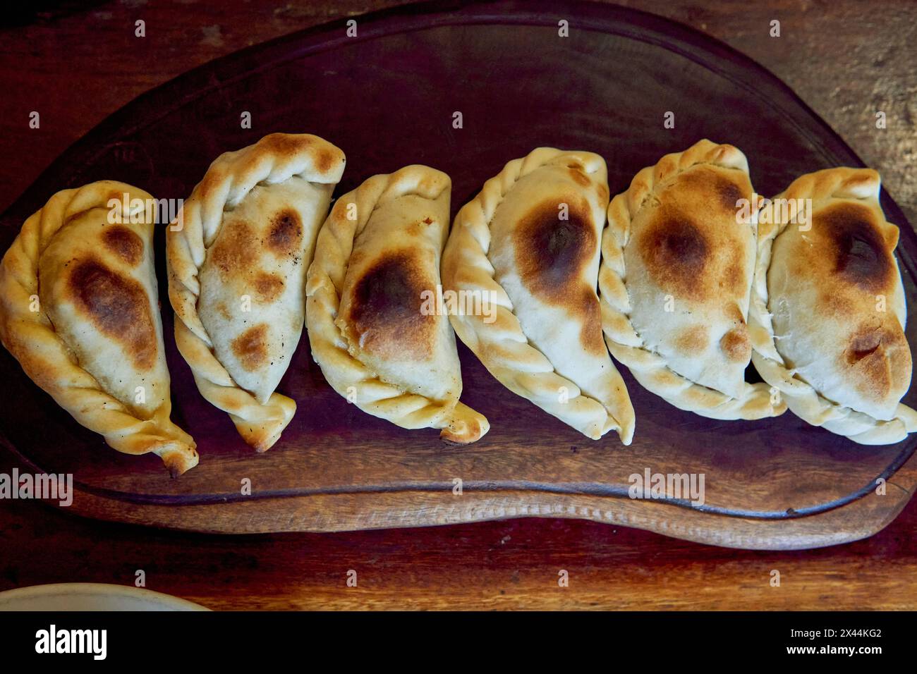 empanadas salteñas su una tavola di legno, ripiena di carne di manzo o di lama, cipolla, patate, peperoncino e spezie. vista dall'alto Foto Stock
