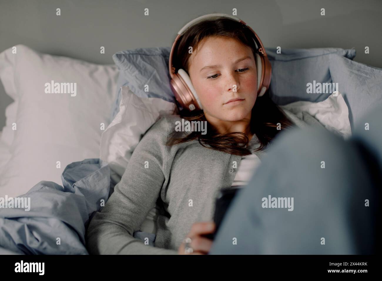 Teenager sdraiata sul letto che guarda un film attraverso un tablet digitale a casa Foto Stock