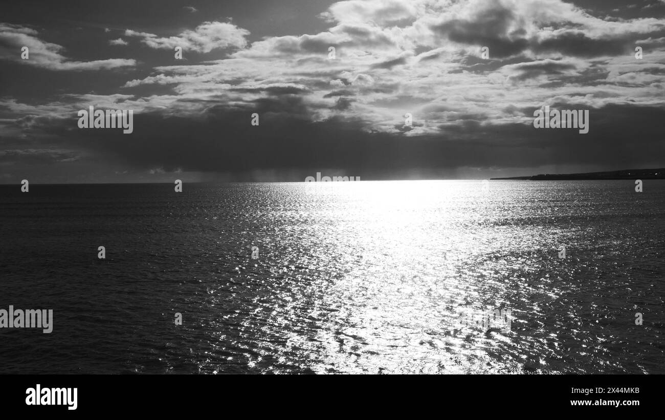 Una nuvola minacciosa all'orizzonte lungo la costa occidentale dell'Irlanda in bianco e nero. Foto Stock