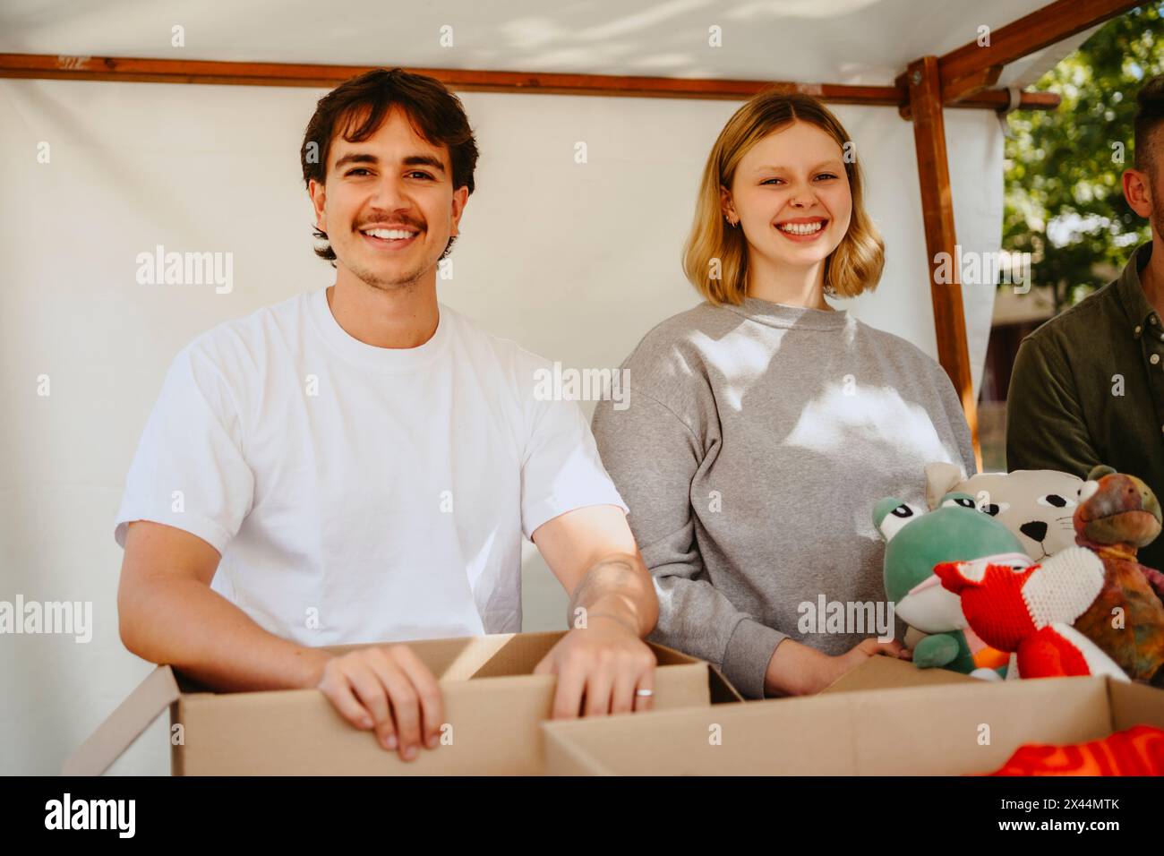 Ritratto di volontari felici con giocattoli ripieni sotto la tenda al centro della comunità Foto Stock