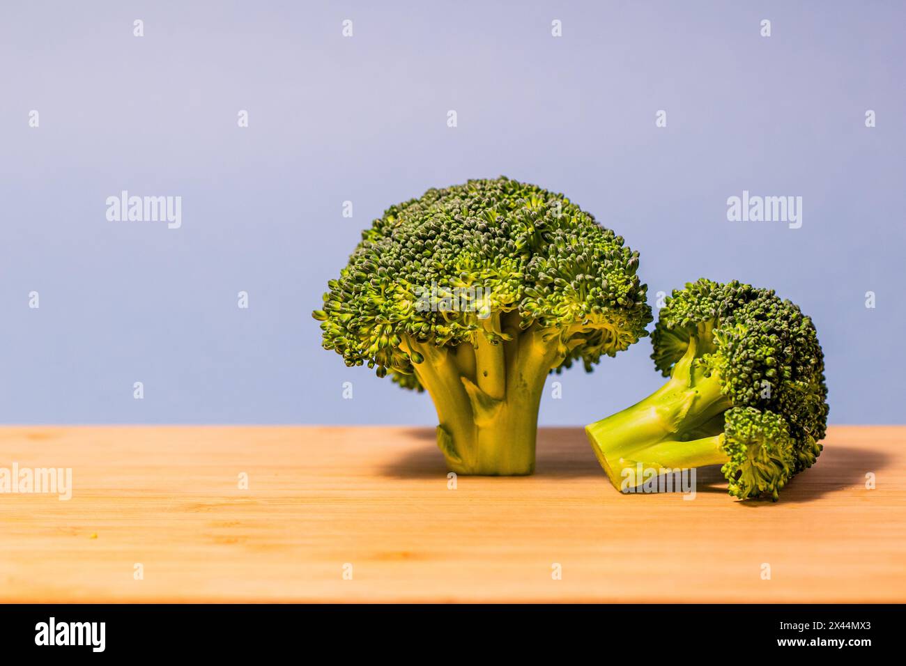 broccoli appena tagliati su un tagliere di legno su sfondo blu Foto Stock