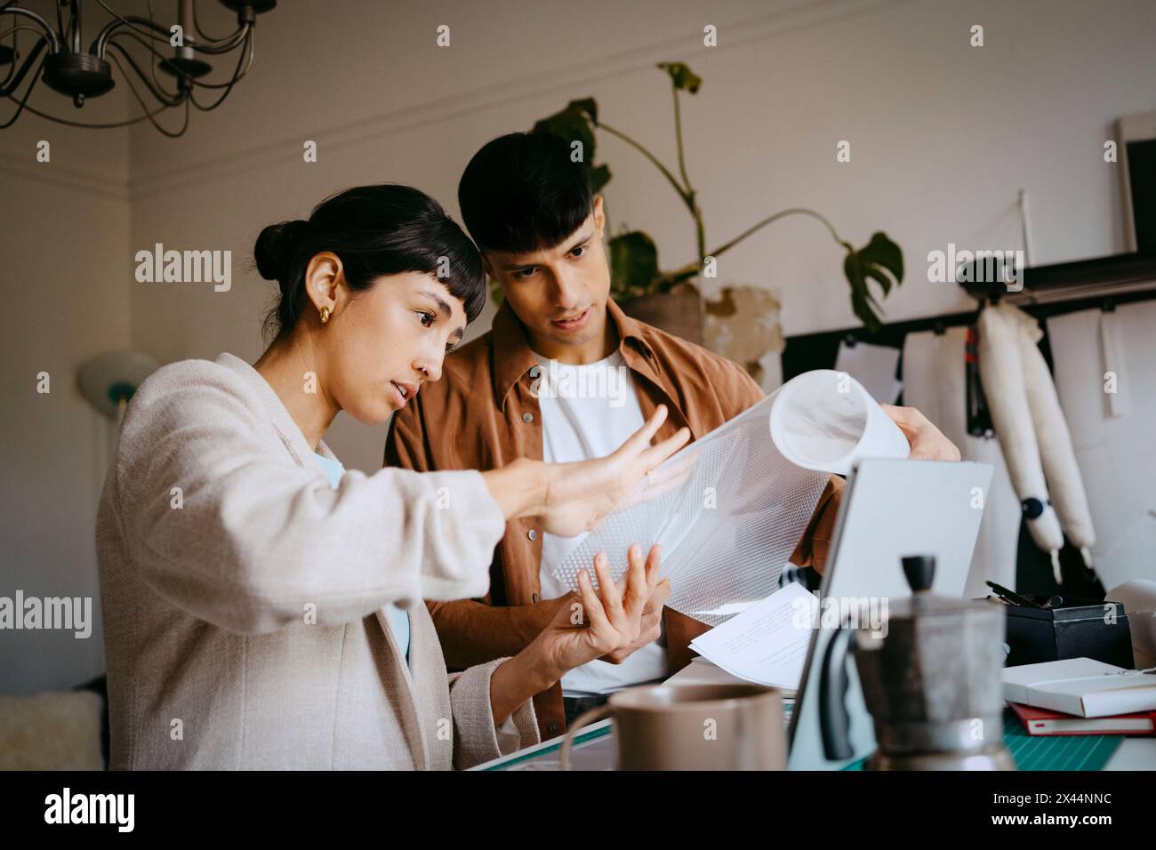 Giovani liberi professionisti maschi e femmine che esaminano pellicole plastiche in ufficio a casa Foto Stock