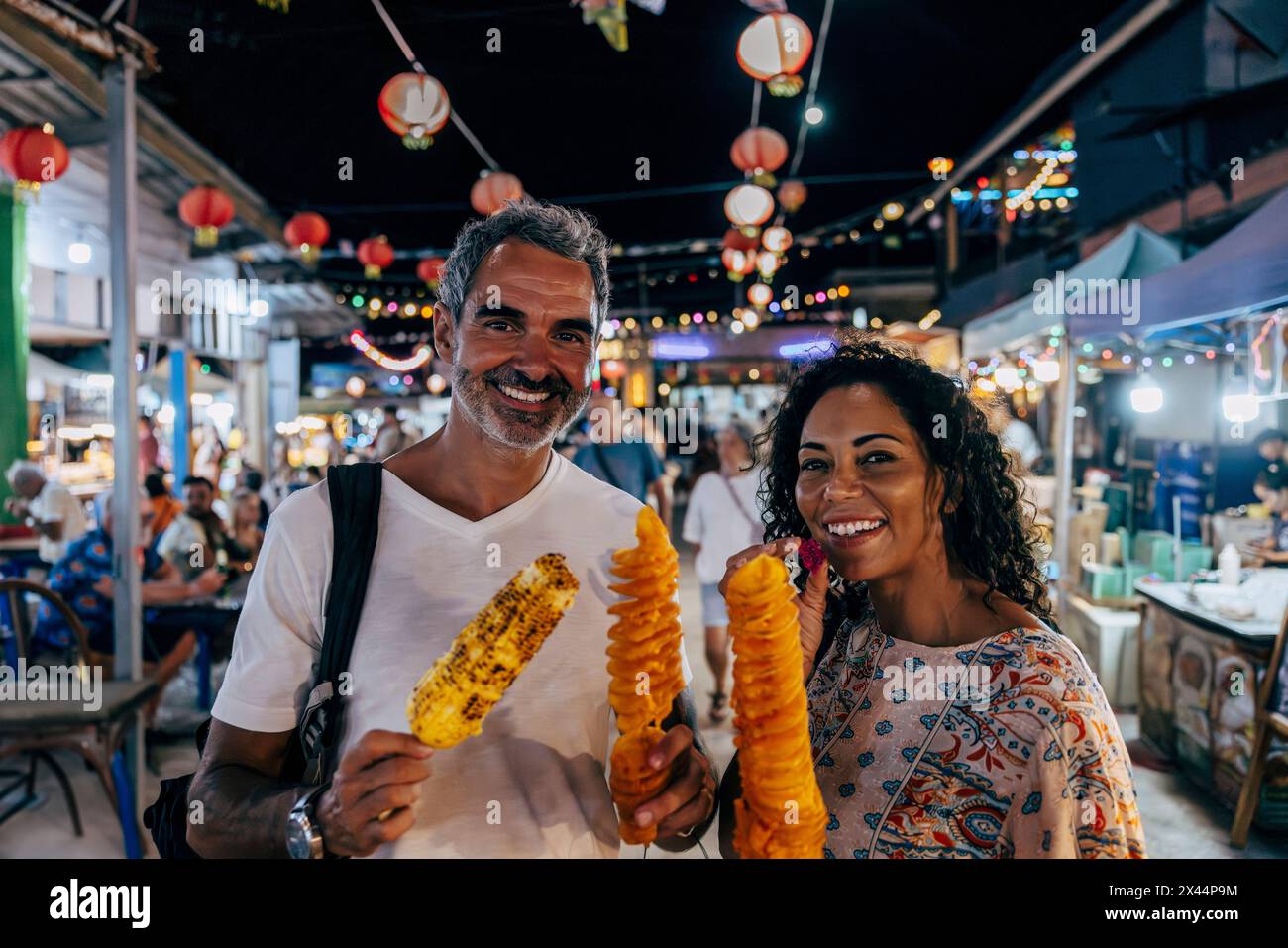 Ritratto di una coppia matura felice che consuma cibo di strada al mercato in vacanza Foto Stock