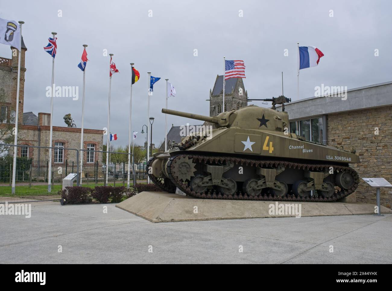 Sainte-Mere-Eglise, Francia - 19 aprile 2024: Museo aereo a Sainte-Mere-Eglise. Carro armato Sherman. Chiesa sullo sfondo. Stile di vita nell'area urbana. Clo Foto Stock