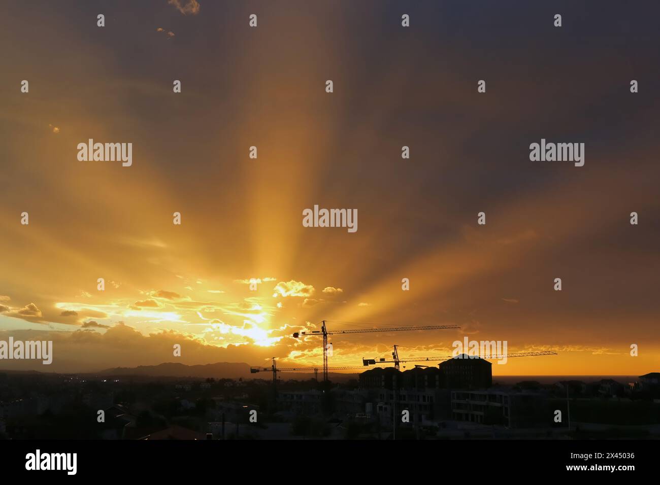 Forte luce solare al crepuscolo sotto la copertura di nuvole pesanti con raggi solari che si irradiano sui sobborghi della città di Santander, Cantabria, Spagna Foto Stock