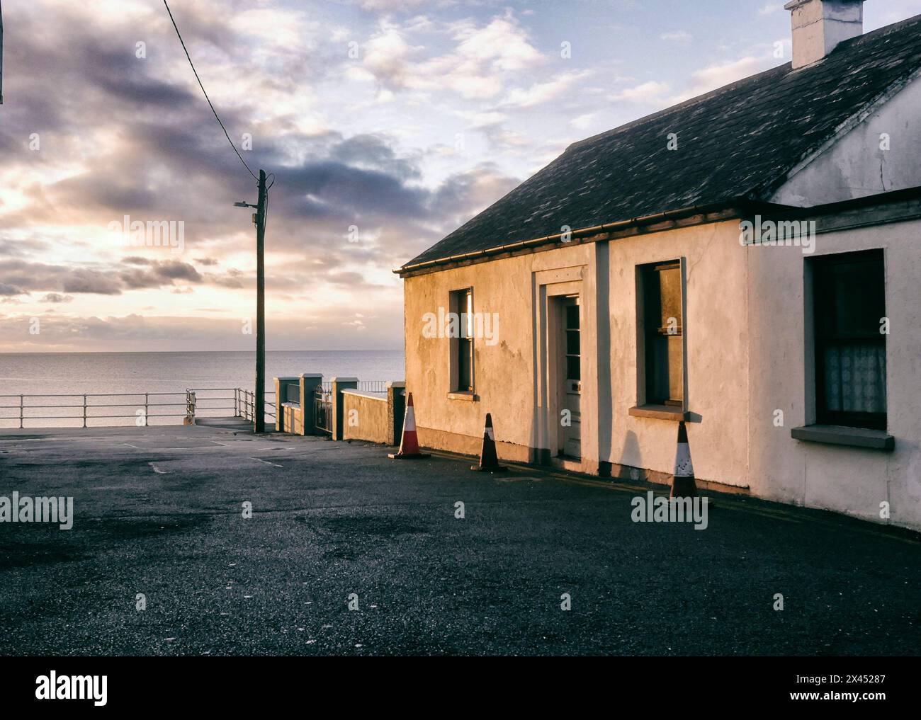 Un cottage sulla costa occidentale dell'Irlanda che riceve l'ultimo raggio di sole. Foto Stock