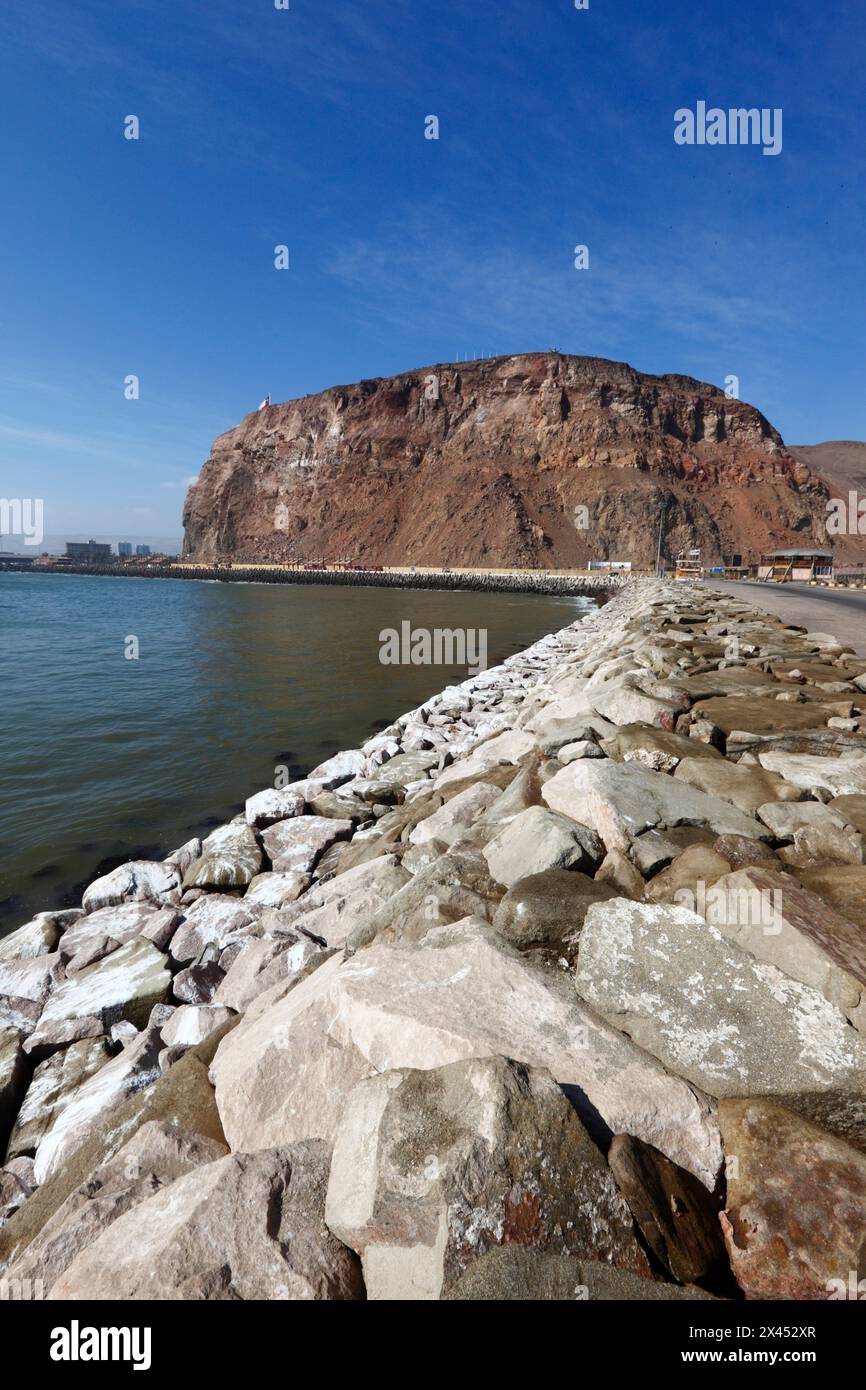 L'ambizione di armature rocciose previene l'erosione costiera accanto alla strada rialzata che collega l'isola di Alacrán alla terraferma e al promontorio di El Morro, Arica, Cile Foto Stock