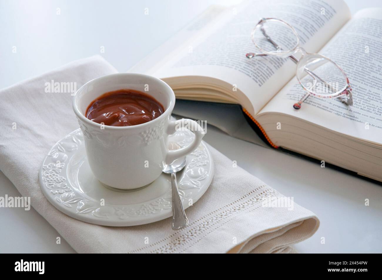 Tazza di cioccolato, libro e occhiali da vista. Foto Stock