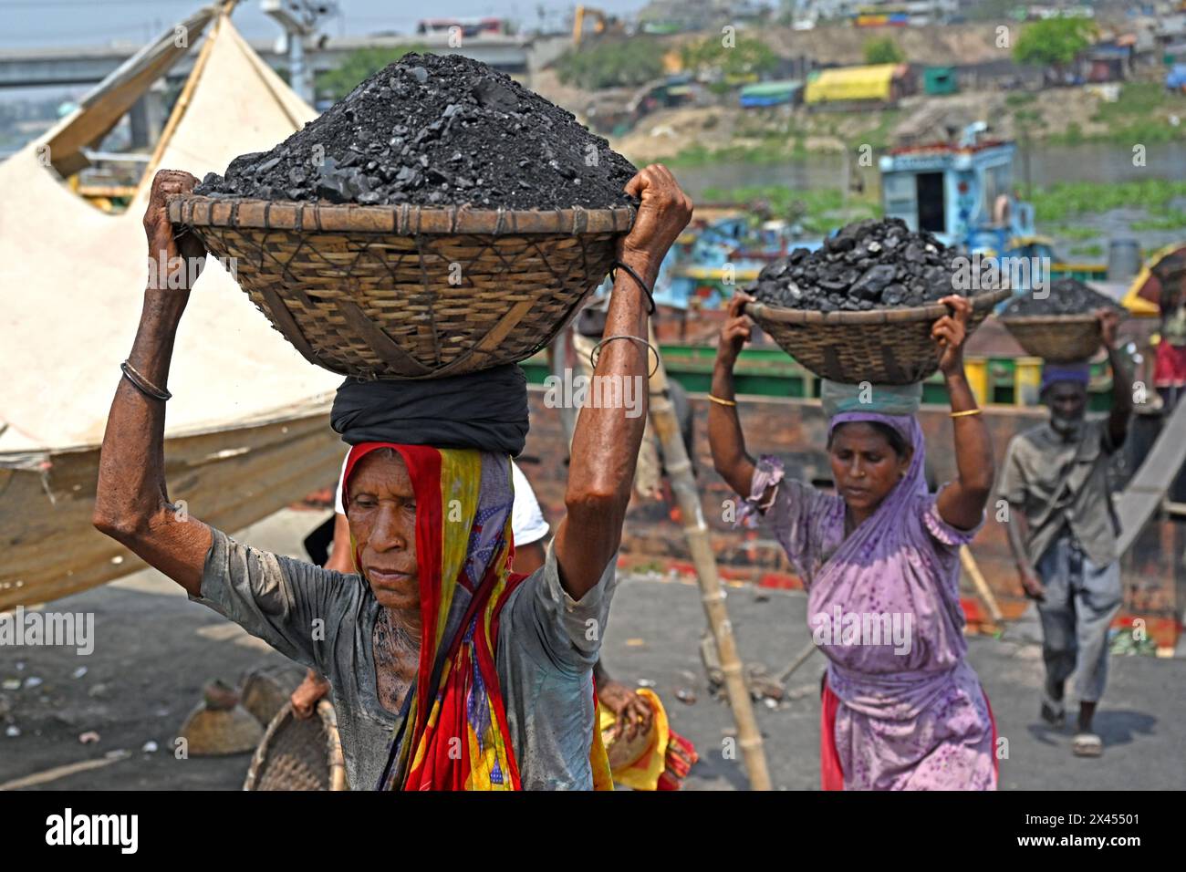 Dacca, Bangladesh, il 30 aprile 2024. Un lavoratore donna scarica carbone da una nave cargo oltre il fiume Turag durante un'ondata di caldo a Dacca, Bangladesh, il 30 aprile 2024. Foto Stock