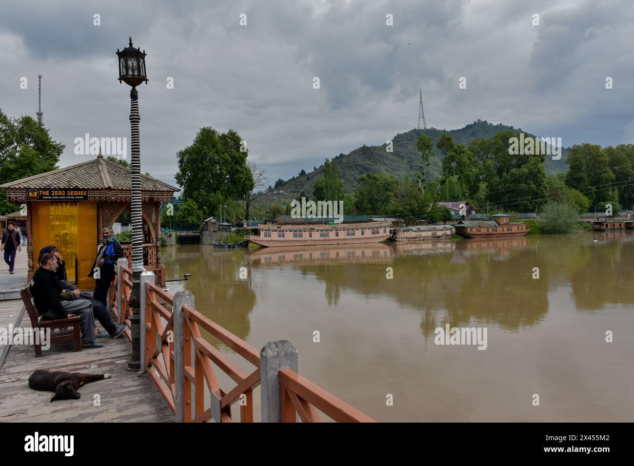 Gli uomini kashmiri riposano su un ponte pedonale mentre il fiume Jhelum scorre sopra il segno di allarme delle inondazioni a seguito di incessanti piogge a Srinagar. Anche se la pioggia si è fermata nel Kashmir, il livello dell'acqua nel fiume Jhelum ha attraversato il marchio della "dichiarazione di inondazione" a Srinagar. Le incessanti piogge hanno colpito molte parti del Jammu e del Kashmir, costringendo l'amministrazione a chiudere le scuole attraverso la valle del Kashmir come misura precauzionale, hanno detto i funzionari. La pioggia ha innescato inondazioni e frane che hanno causato danni alle infrastrutture pubbliche. Il dipartimento meteorologico aveva previsto delle docce luminose nel vall Foto Stock