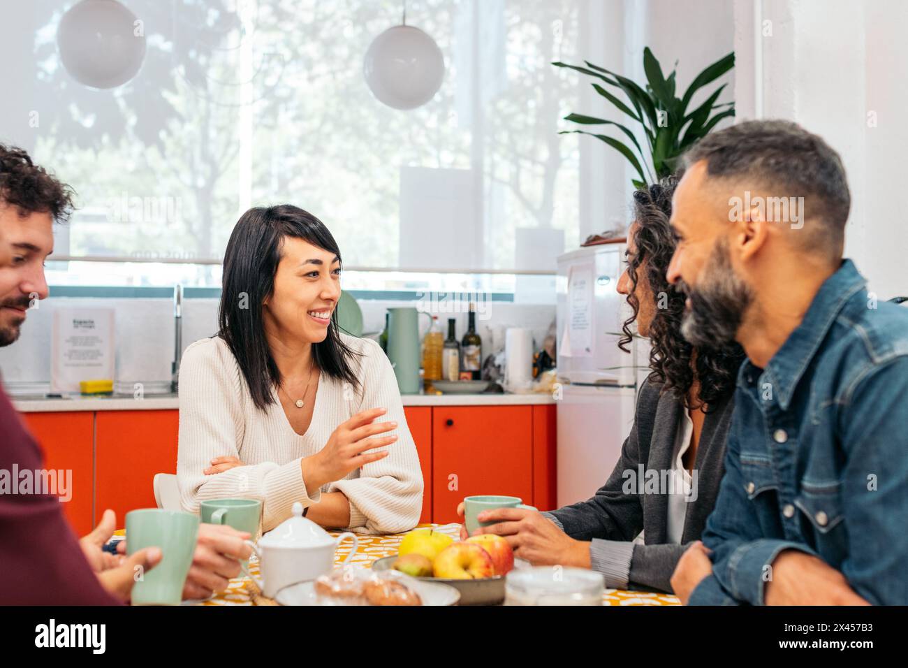 I colleghi mangiano felicemente nella cucina di un ufficio di coworking durante una pausa Foto Stock