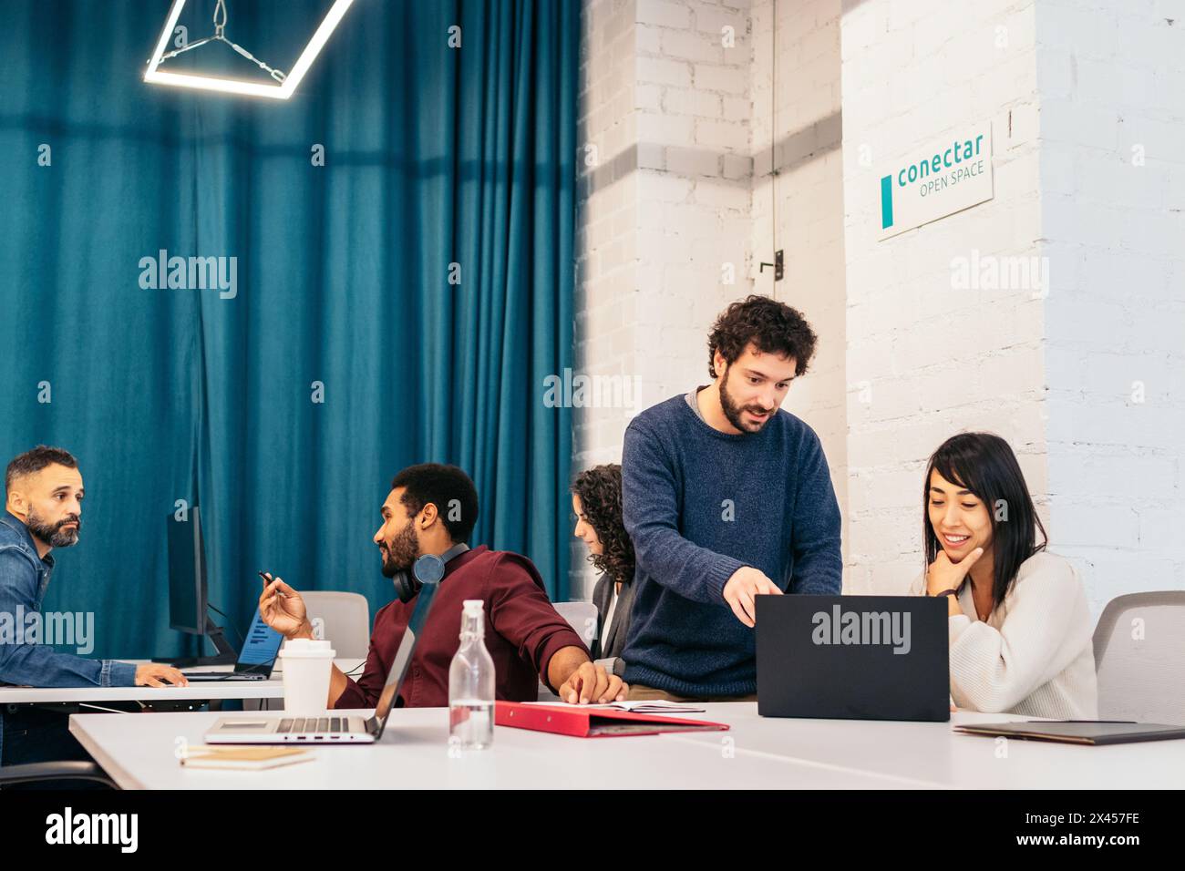 Gruppo di persone di diverse razze che lavorano concentrati e soddisfatti dei notebook in un ufficio di coworking Foto Stock