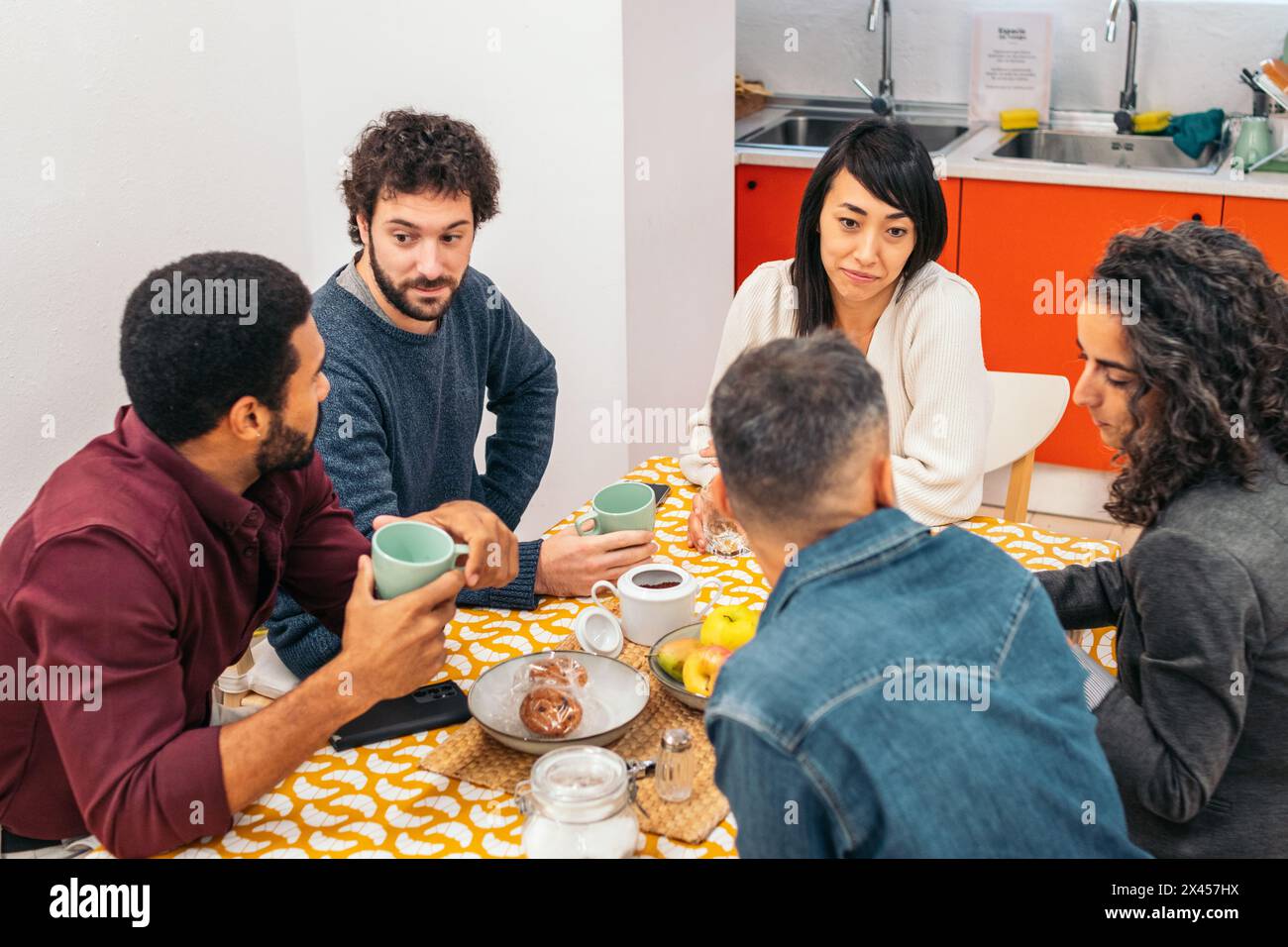 I colleghi mangiano felicemente nella cucina di un ufficio di coworking durante una pausa Foto Stock