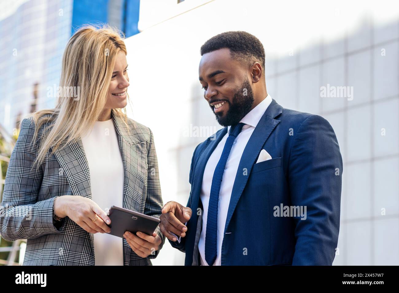 Gli uomini d'affari in abiti da ufficio che usano un tablet che parla dei dati aziendali fuori dall'ufficio Foto Stock