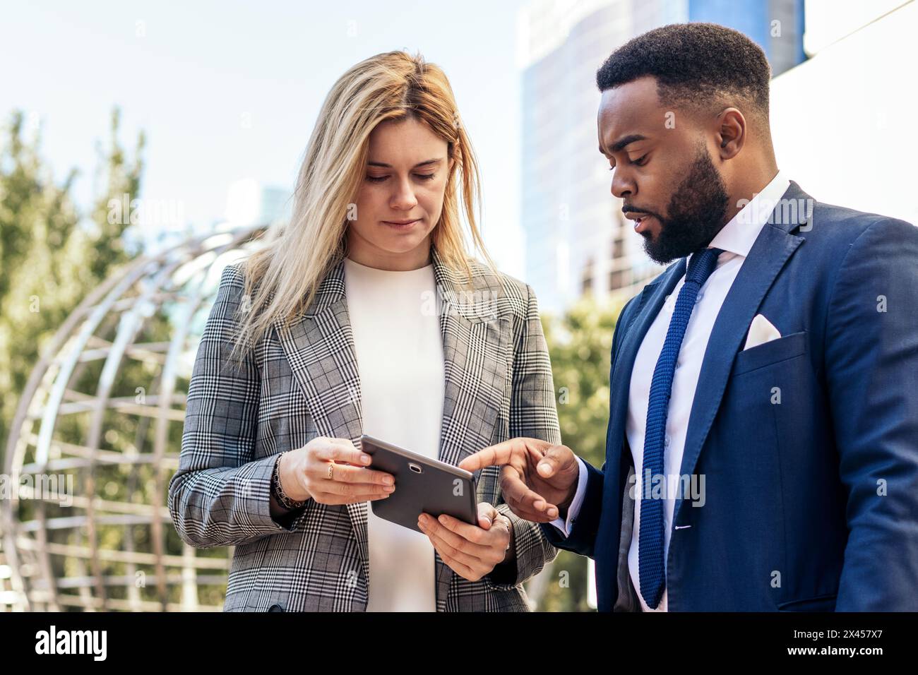 Gli uomini d'affari in abiti da ufficio che usano un tablet che parla dei dati aziendali fuori dall'ufficio Foto Stock