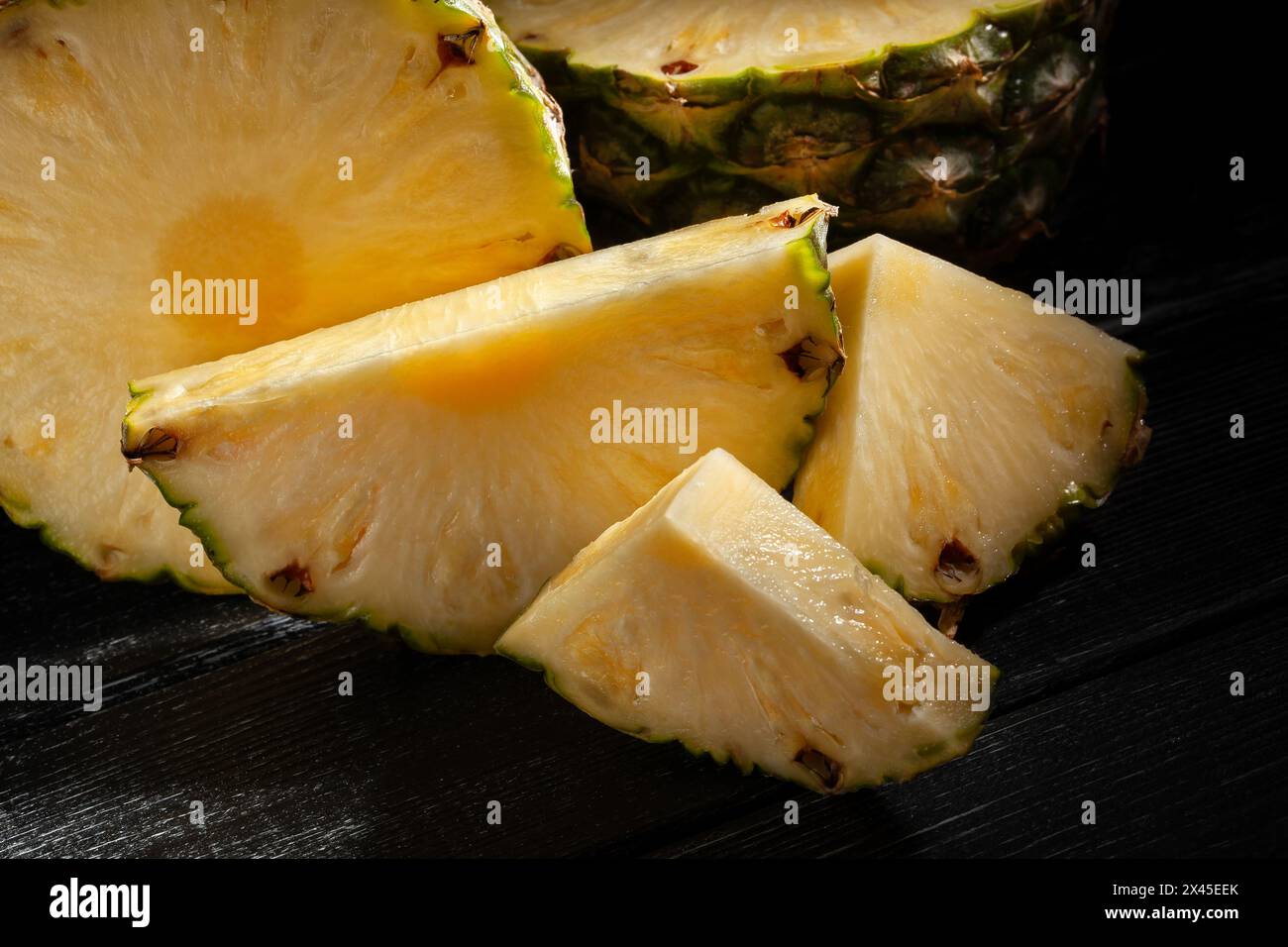 ananas tagliato a fette su sfondo di legno nero Foto Stock