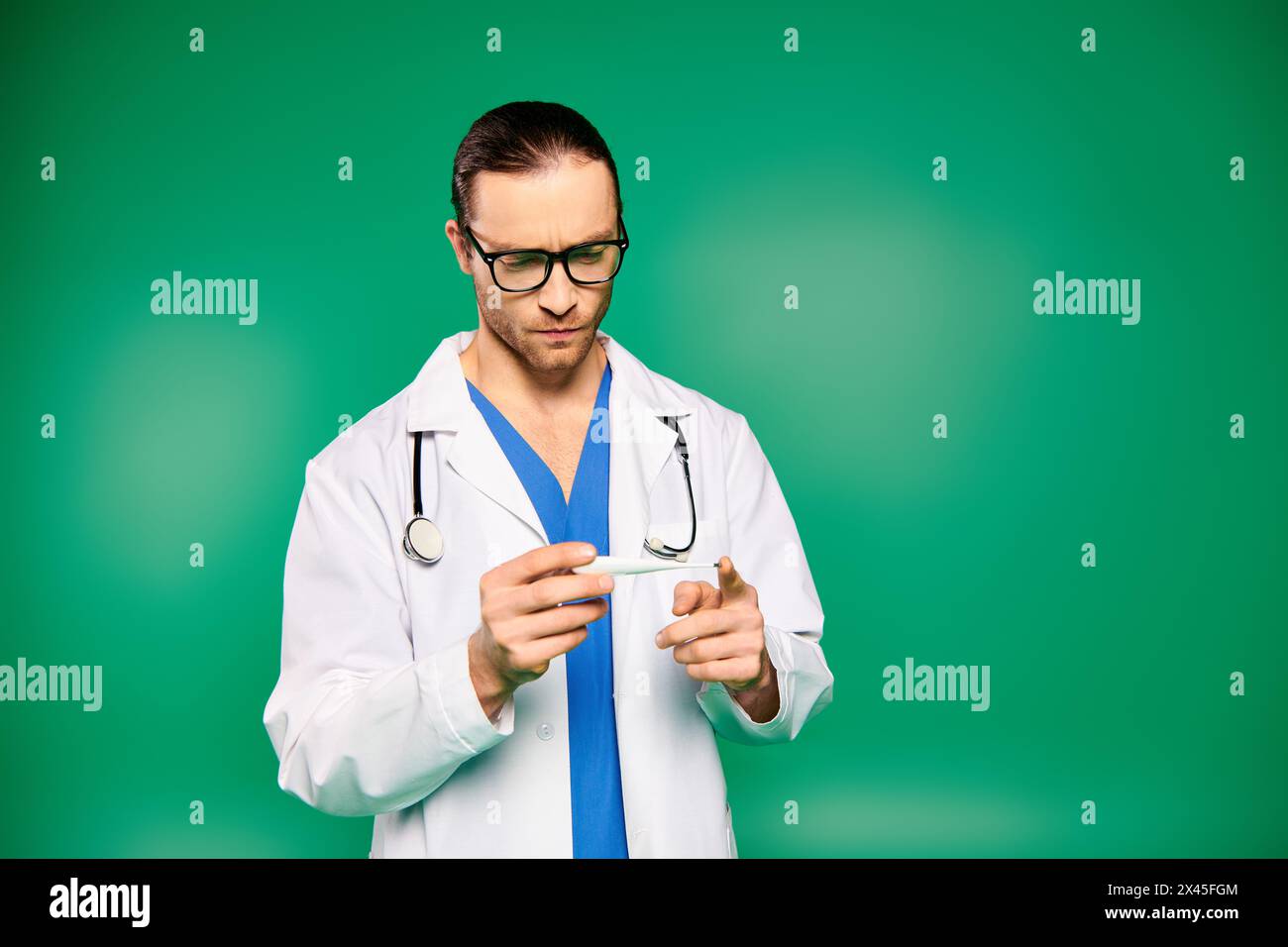 Un medico di sesso maschile con un camice bianco e un paio di occhiali esamina il termometro con attenzione. Foto Stock
