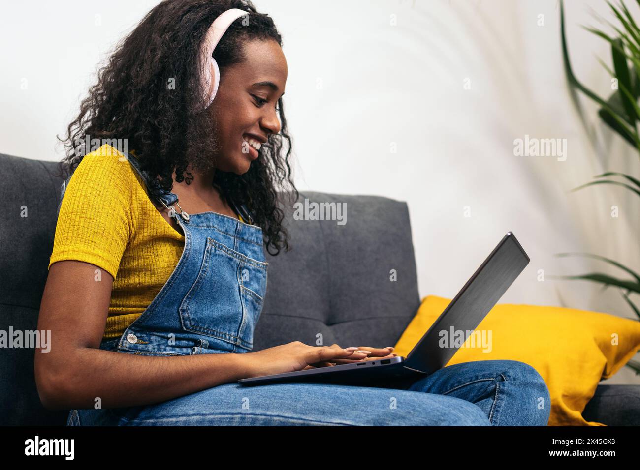 Giovane donna nera che si diverte a casa con il suo stile di vita digitale, perfetta per contenuti e marketing legati alla tecnologia Foto Stock