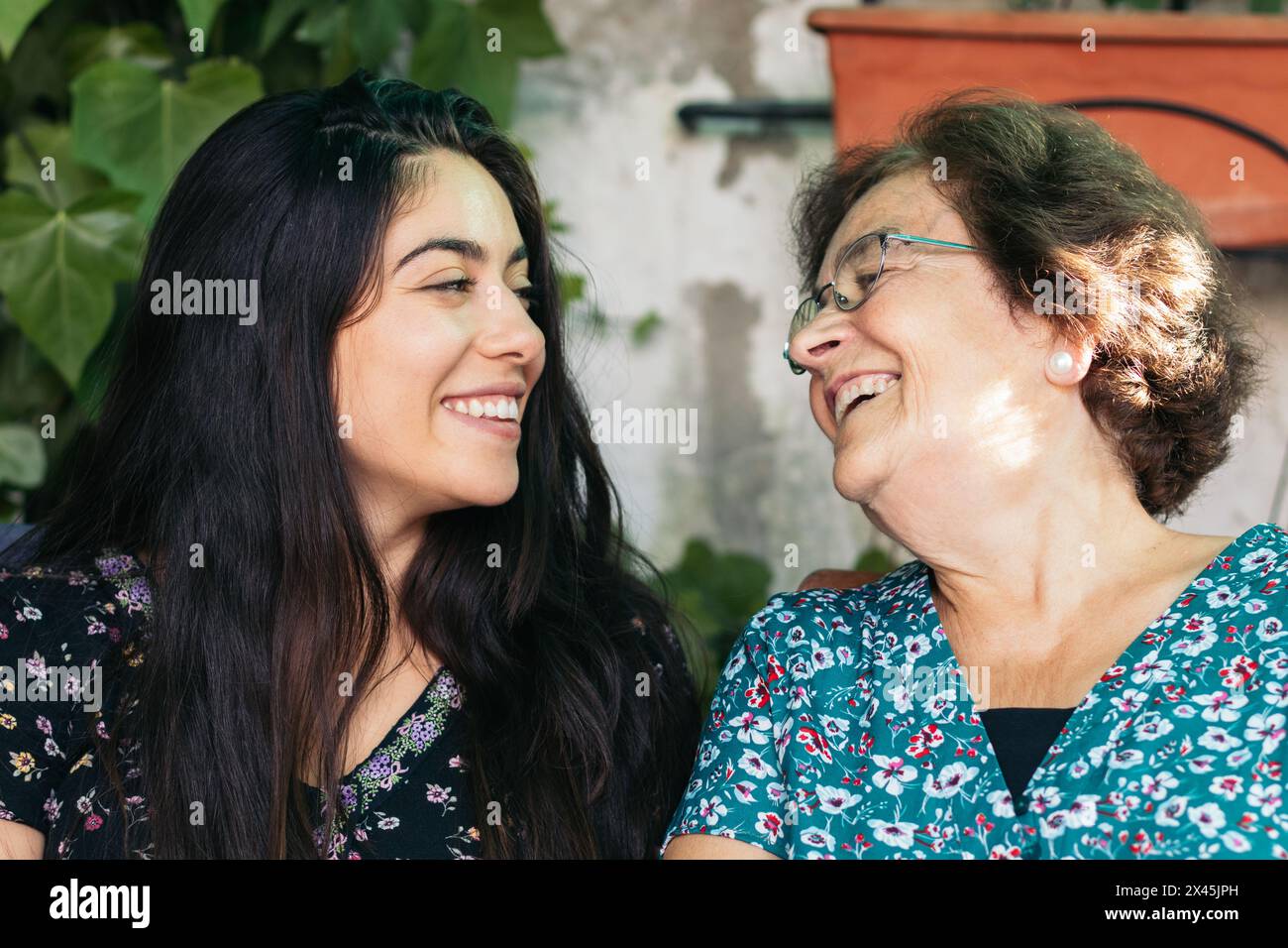 Nonna e nipote che parlano e ridono insieme seduti nel cortile della casa Foto Stock