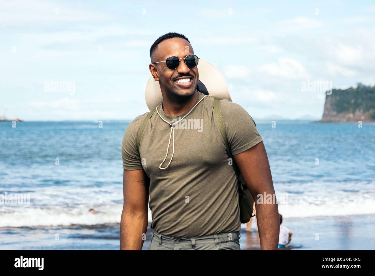 Ritratto di un uomo afroamericano che indossa occhiali da sole e cappello in un paesaggio marino in una giornata di sole Foto Stock