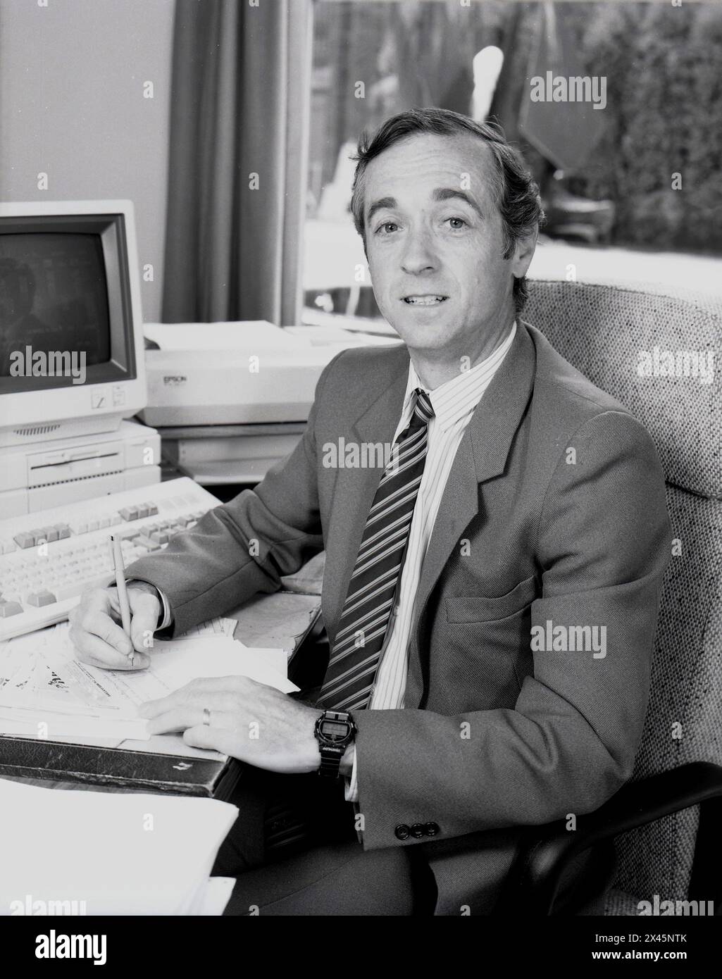 1987, un dirigente d'affari maschile alla sua scrivania, un contabile o un contabile, che scrive un assegno. Un monitor di computer dell'epoca, un VT320 digitale accanto a lui. Il VT320 prodotto dalla Digital Equipment Corporation (DEC) era un terminale informatico popolare in quest'epoca per l'elaborazione dei dati, comunemente usato nelle biblioteche per la catalogazione dei libri. Foto Stock