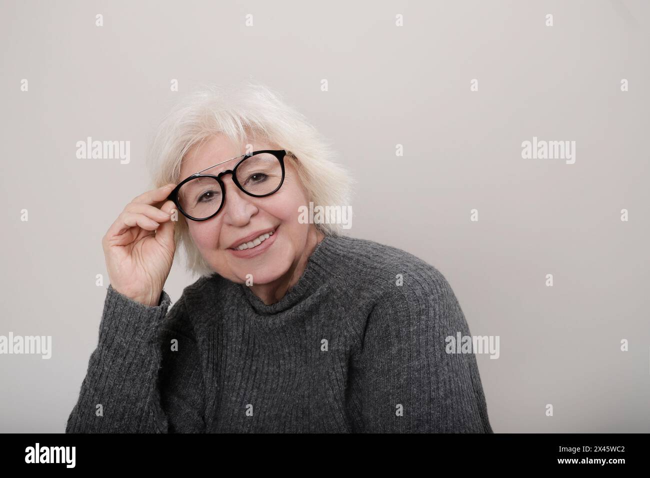 donna anziana dai capelli grigi che sorride alla fotocamera con gli occhiali Foto Stock