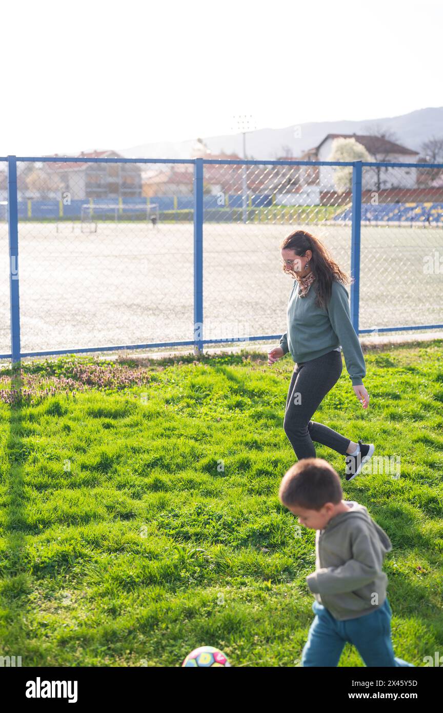 Con una formica vigile nelle vicinanze, un bambino conduce un inseguimento, incarnando la gioia del calcio a 3 anni sul campo erboso Foto Stock