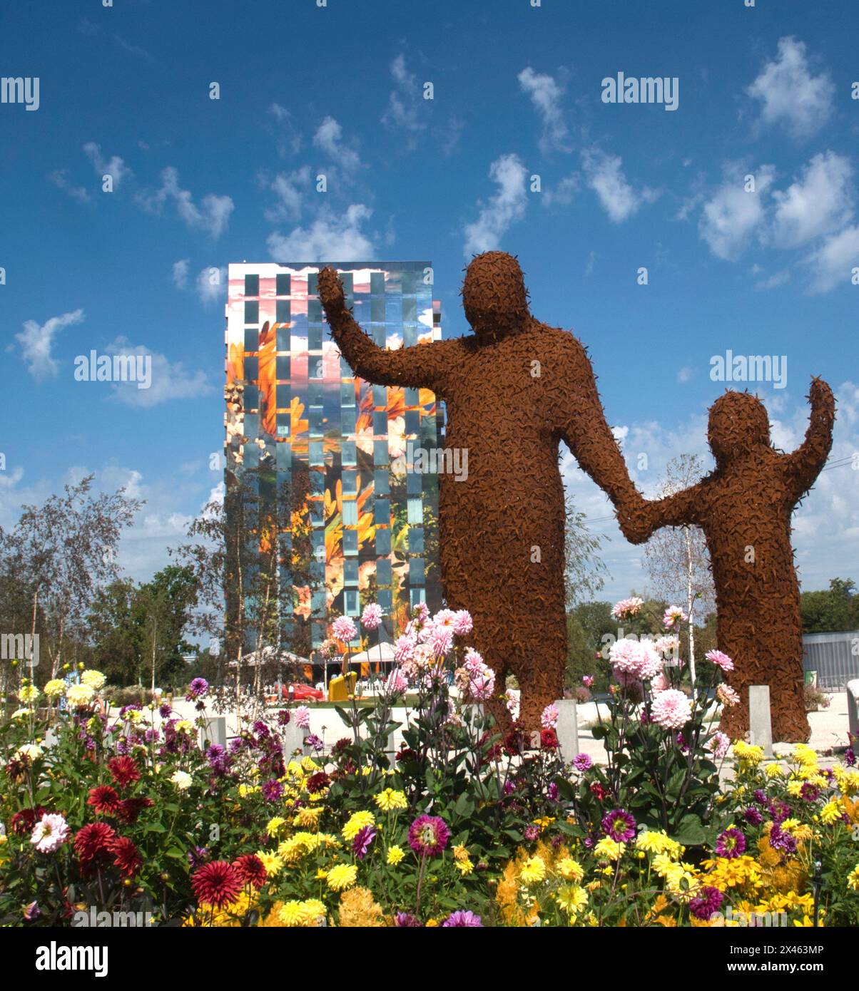 Figure scultoree "Behold" di Florentijn Hofman con la Torre dipinta Flores alle spalle al Floriade Expo 2022, Almere, Paesi Bassi Foto Stock