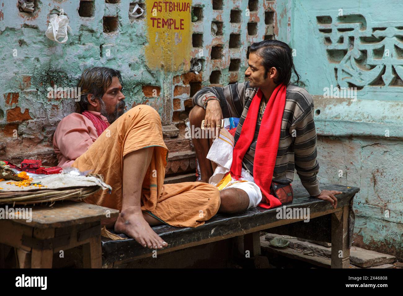 Due uomini che parlavano mentre si dilettavano su una panchina a Varanasi, in India. Foto Stock