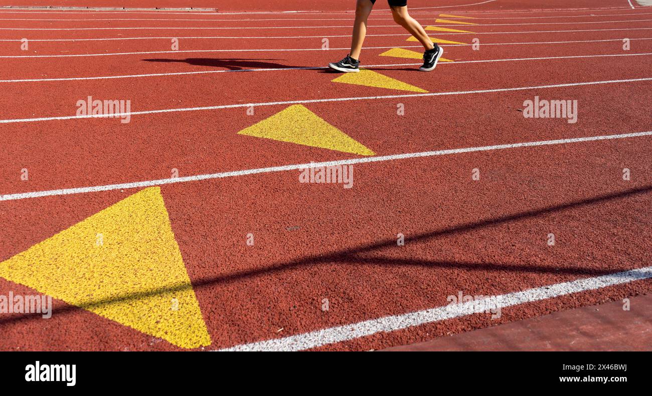 Vista parziale di un atleta che corre su una corsia della pista di atletica in un centro sportivo all'aperto di Parigi in una giornata di sole Foto Stock
