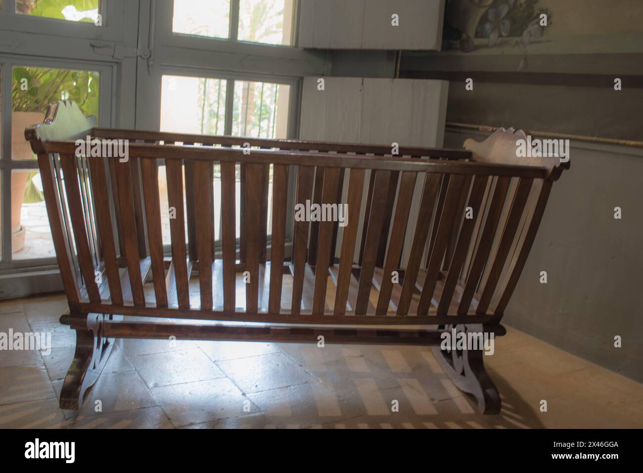 Vecchia culla di legno vicino alla finestra Foto Stock