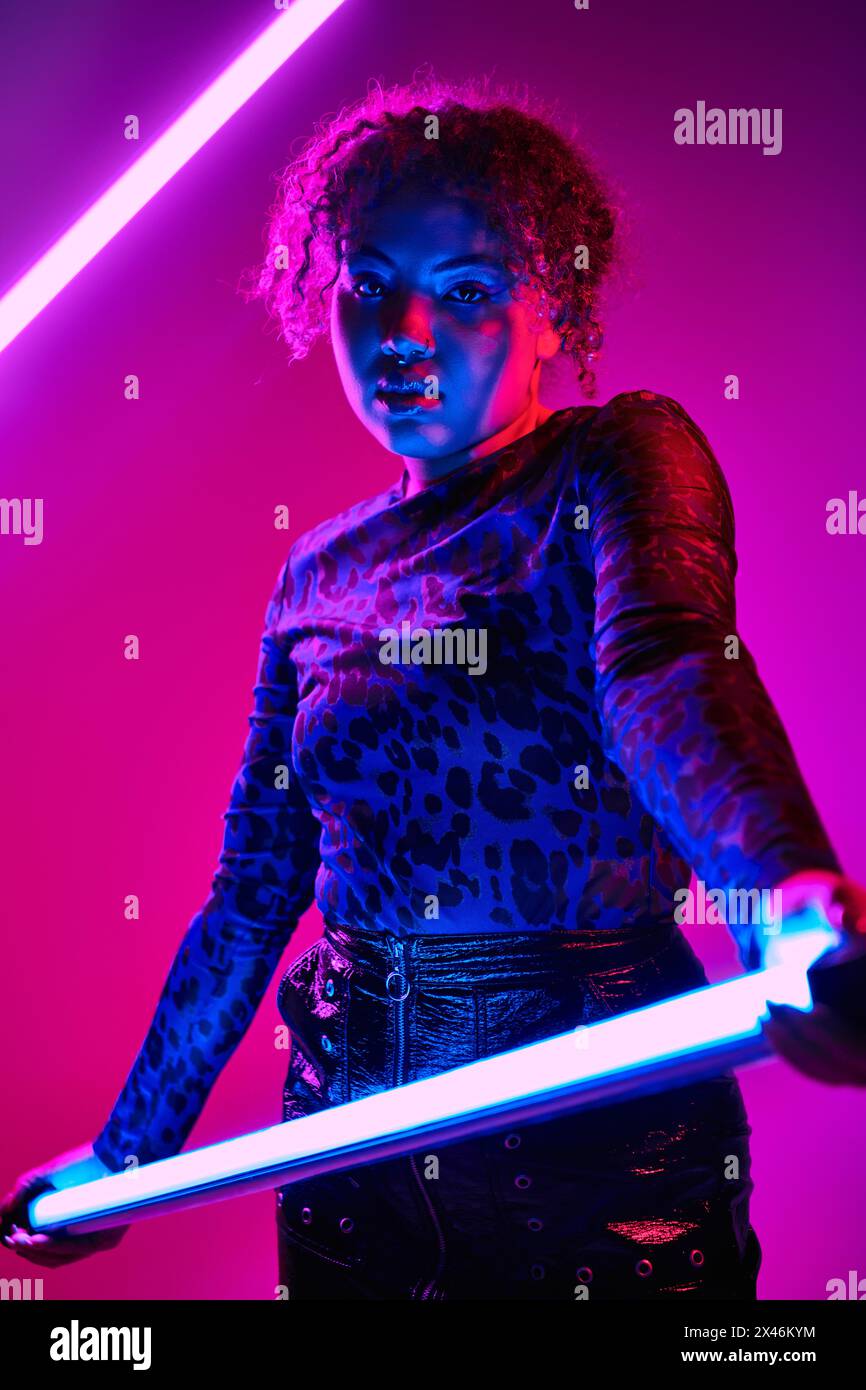 Una splendida donna afroamericana porta una lampada a LED in una stanza poco illuminata. Foto Stock