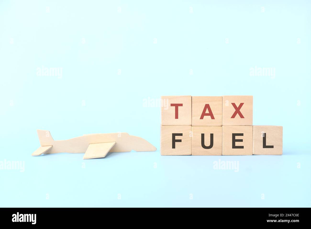 Concetto di tassa sul carburante per l'aviazione. Tipografia con blocchi di legno su sfondo blu. Foto Stock
