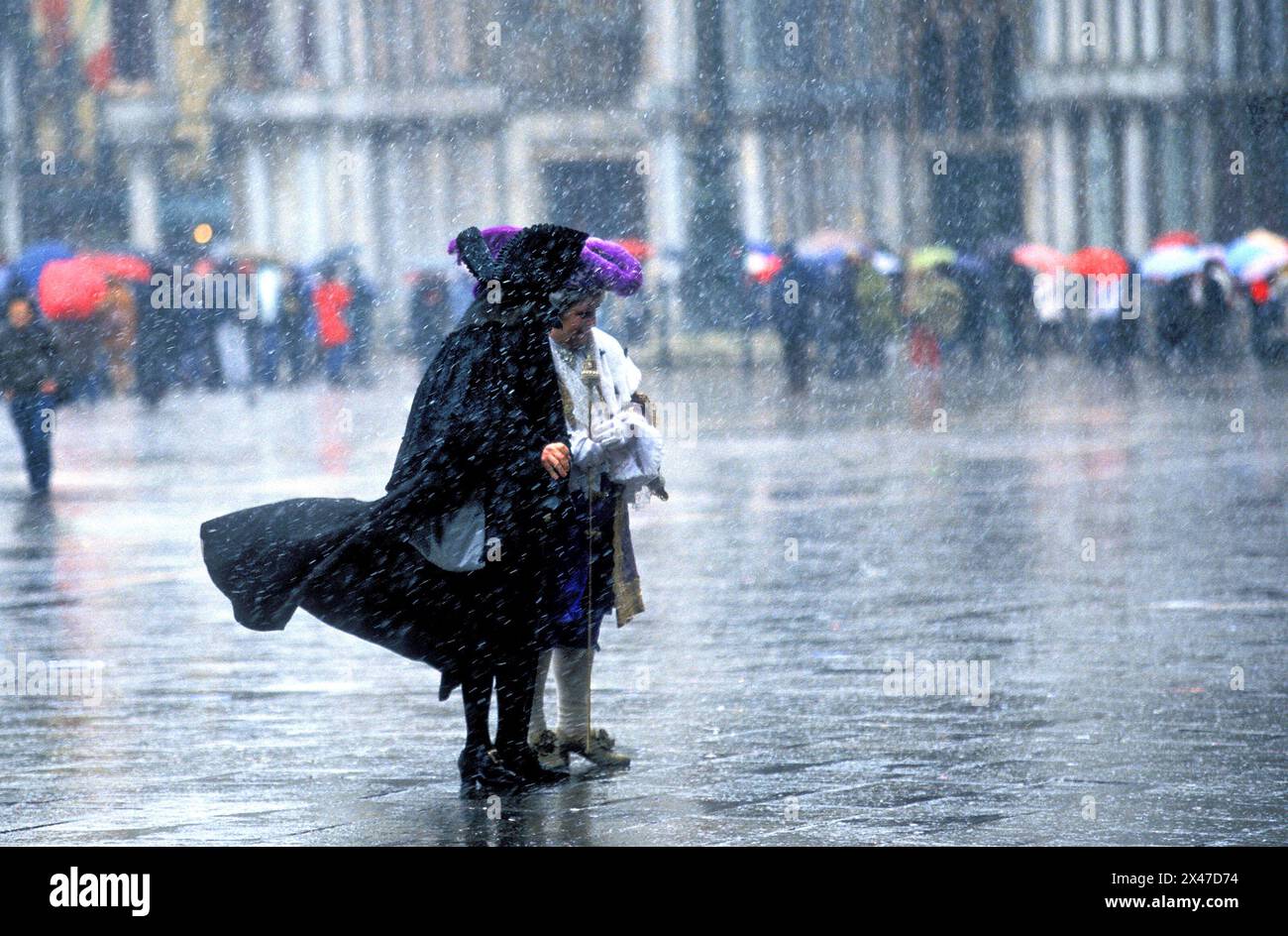 Persone vestite con costumi di carnevale in piedi in condizioni di maltempo, St Marko, Venezia, Italia Foto Stock