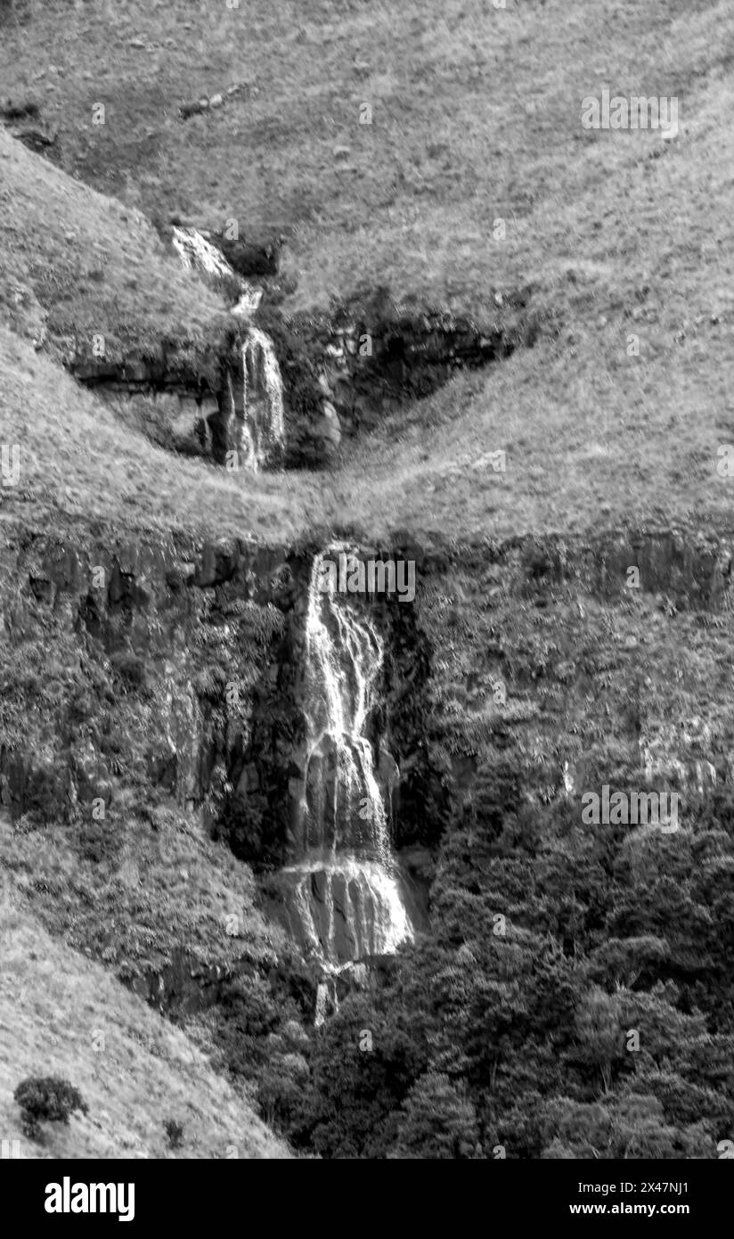 Vista in bianco e nero di una cascata tra le scogliere delle praterie Afromontane delle montagne Drakensberg in Sudafrica Foto Stock